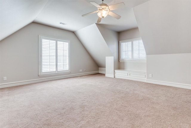 additional living space with carpet, vaulted ceiling, a wealth of natural light, and ceiling fan