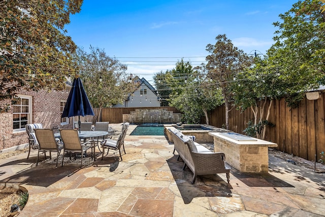 view of patio / terrace with a swimming pool with hot tub and an outdoor fire pit