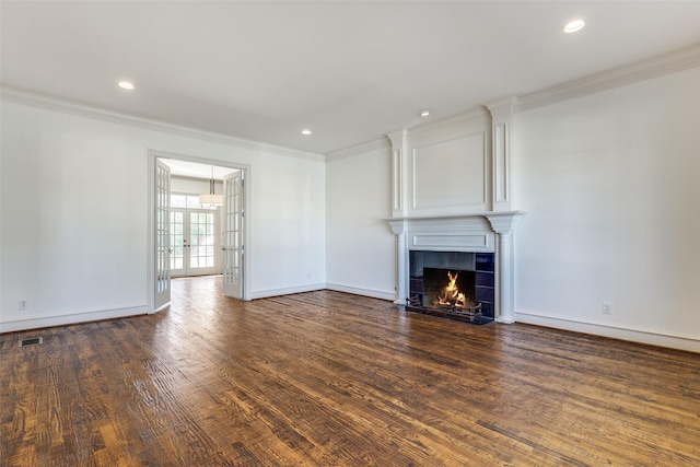 unfurnished living room featuring dark hardwood / wood-style floors, french doors, crown molding, and a tiled fireplace