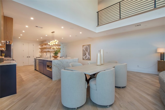 dining room featuring sink, a high ceiling, and light wood-type flooring