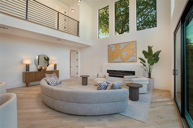 living room with light wood-type flooring and a towering ceiling