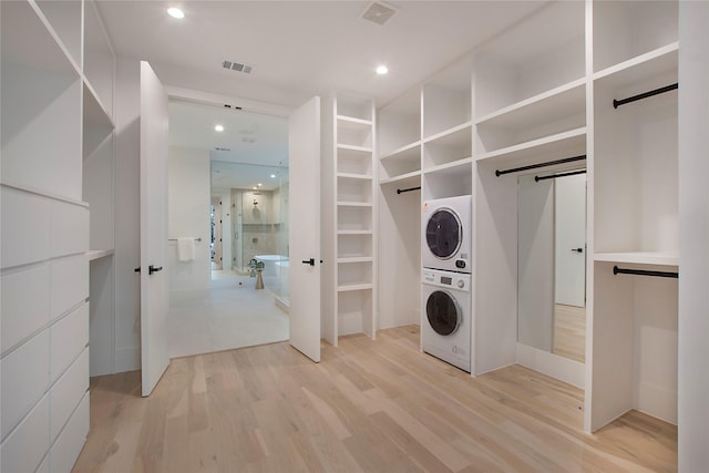 washroom featuring stacked washer / dryer, light hardwood / wood-style floors, and a barn door