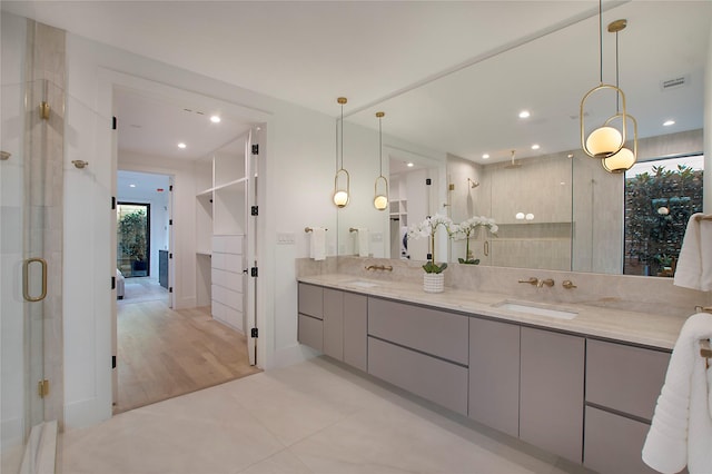 bathroom with tile patterned flooring, vanity, a shower with door, and a wealth of natural light