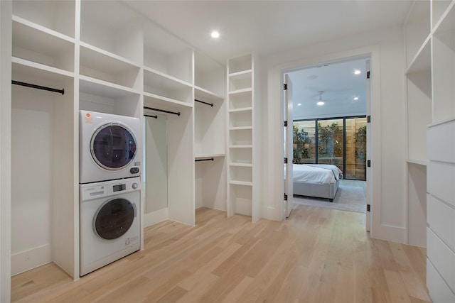 laundry room with wood-type flooring, a barn door, and stacked washing maching and dryer