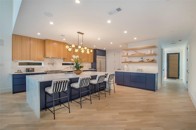 kitchen with a kitchen bar, light wood-type flooring, light stone counters, decorative light fixtures, and a large island