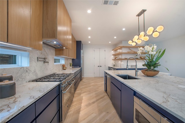 kitchen with hanging light fixtures, sink, light wood-type flooring, light stone countertops, and appliances with stainless steel finishes