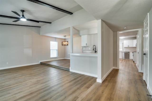 interior space featuring white cabinetry, light hardwood / wood-style flooring, stainless steel dishwasher, kitchen peninsula, and ceiling fan with notable chandelier