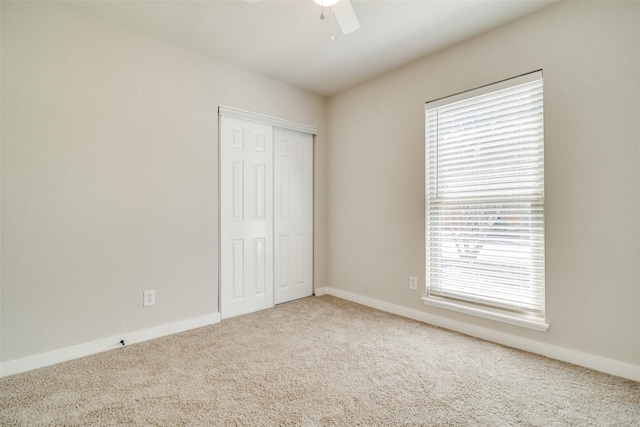 unfurnished bedroom featuring ceiling fan, a closet, carpet floors, and multiple windows