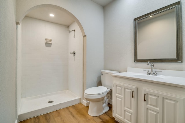 bathroom featuring tiled shower, vanity, hardwood / wood-style flooring, and toilet