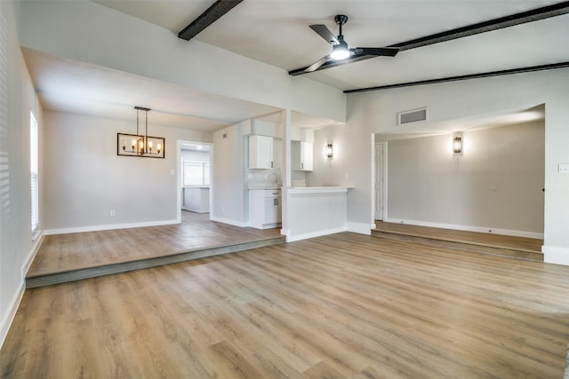 unfurnished living room featuring beamed ceiling, ceiling fan with notable chandelier, and light wood-type flooring