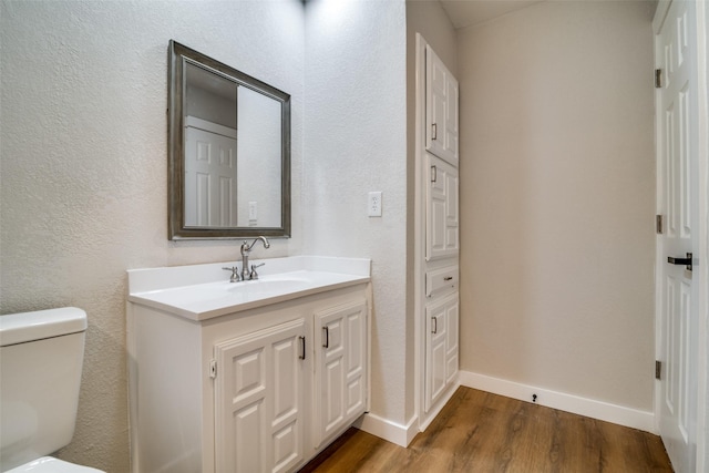 bathroom with hardwood / wood-style floors, vanity, and toilet