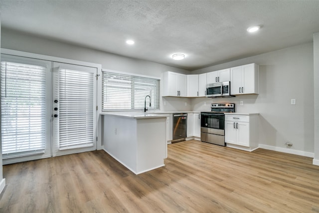 kitchen with white cabinets, stainless steel appliances, light hardwood / wood-style flooring, and plenty of natural light