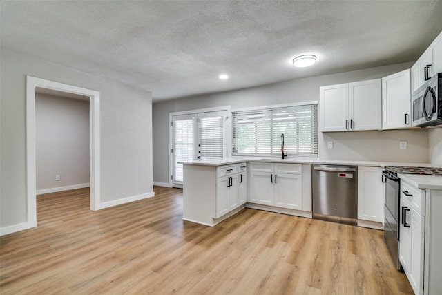 kitchen with light hardwood / wood-style floors, white cabinetry, sink, and appliances with stainless steel finishes