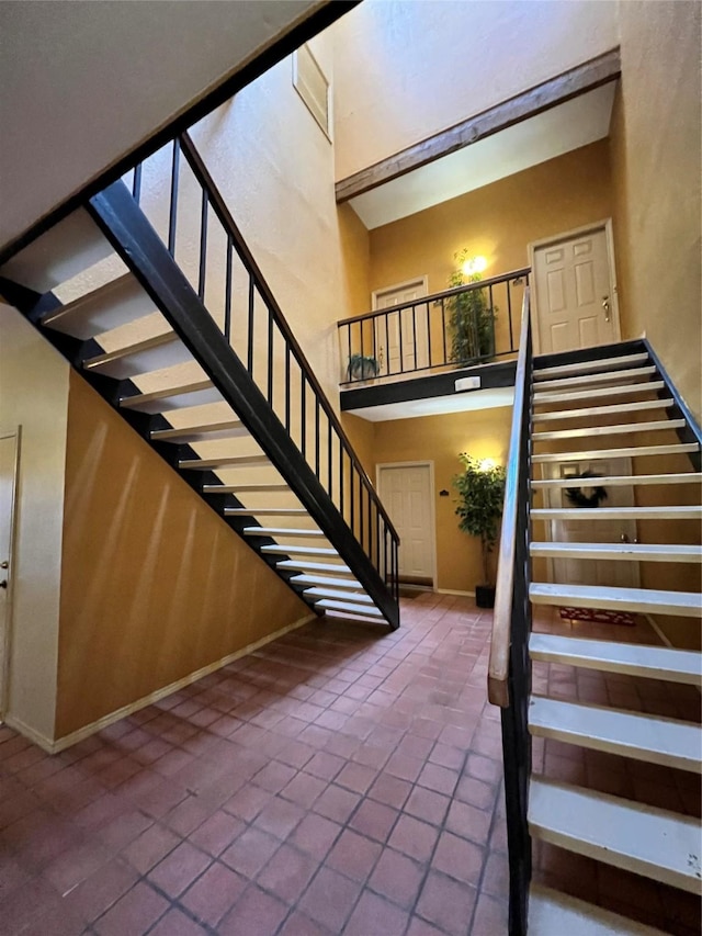 stairs with tile patterned flooring and a high ceiling