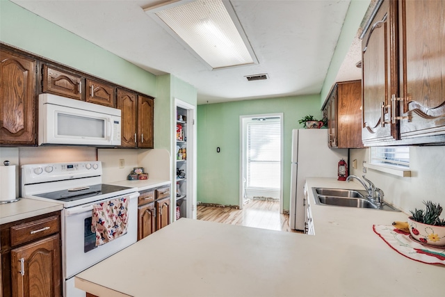 kitchen featuring kitchen peninsula, white appliances, and sink