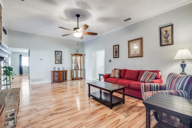 living room featuring ceiling fan, light hardwood / wood-style flooring, crown molding, and a textured ceiling