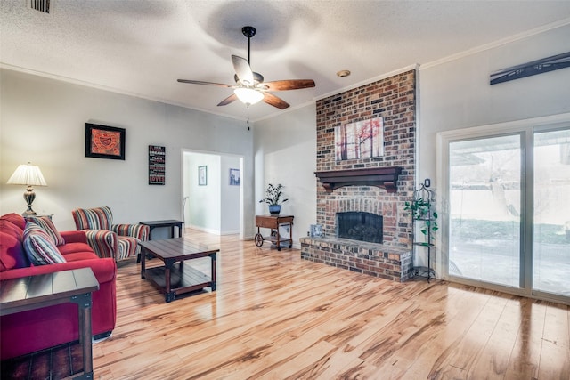 living room with a textured ceiling, a brick fireplace, ceiling fan, and ornamental molding