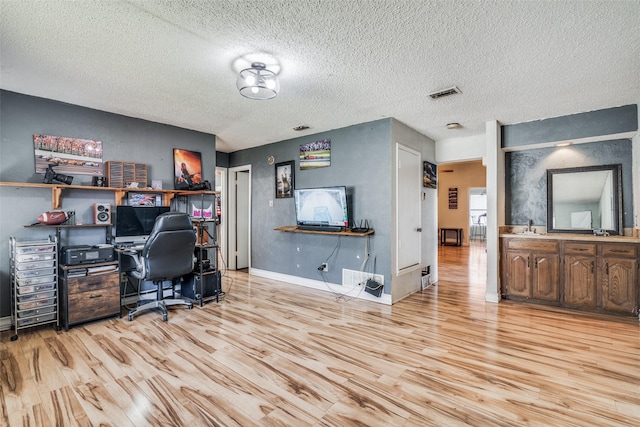 office featuring light hardwood / wood-style flooring, a textured ceiling, and sink