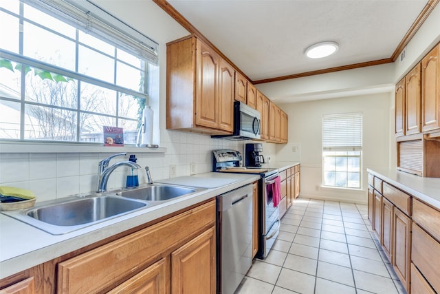 kitchen with tasteful backsplash, sink, crown molding, stainless steel appliances, and light tile patterned floors