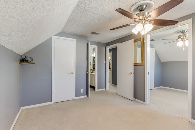 additional living space featuring ceiling fan, light colored carpet, vaulted ceiling, and a textured ceiling