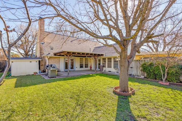 rear view of house with a lawn and a patio