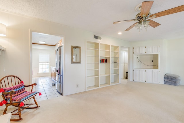 sitting room with a textured ceiling, ceiling fan, built in features, and light colored carpet