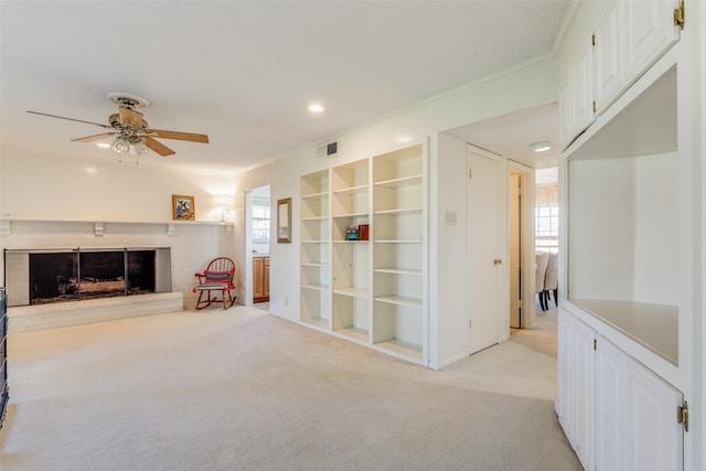 interior space featuring ceiling fan, light colored carpet, a brick fireplace, and built in shelves