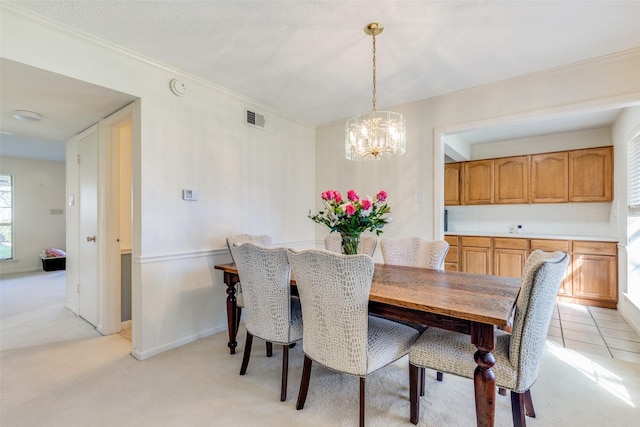 carpeted dining room with an inviting chandelier and ornamental molding