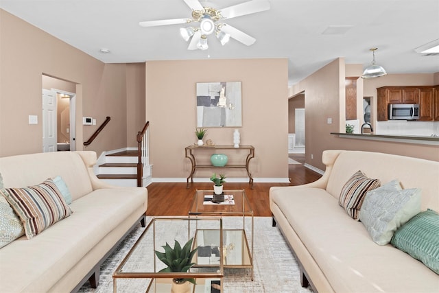 living room with hardwood / wood-style flooring, ceiling fan, and sink