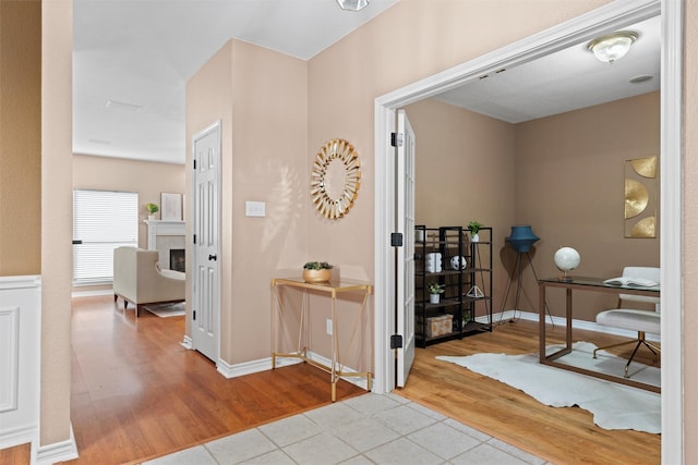 interior space with a tiled fireplace, wood finished floors, and baseboards