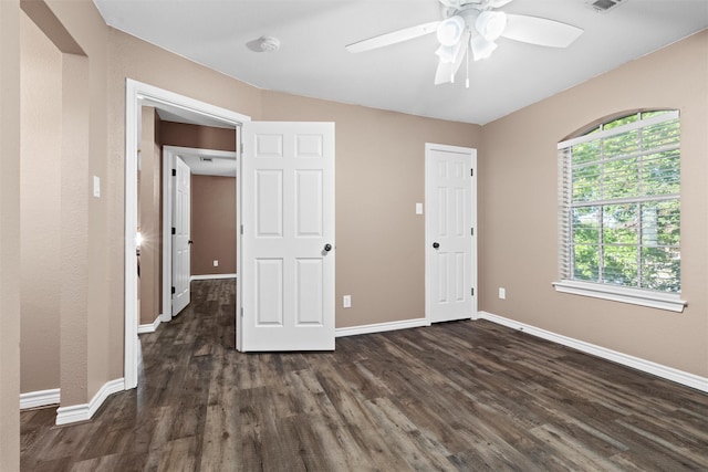 unfurnished bedroom with a ceiling fan, visible vents, dark wood-style floors, and baseboards