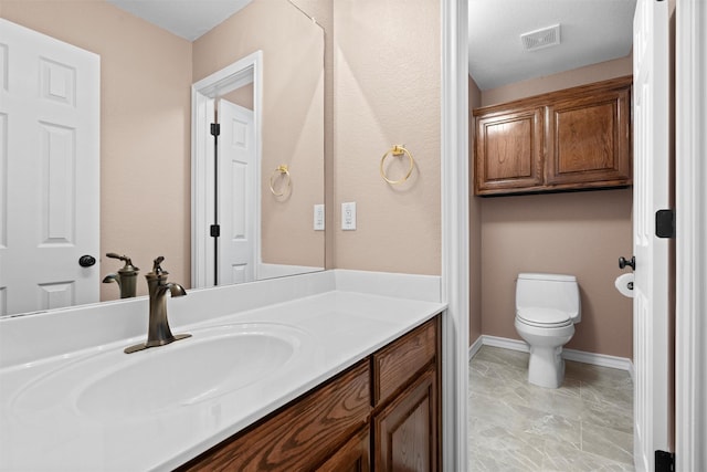 bathroom with visible vents, toilet, vanity, and baseboards