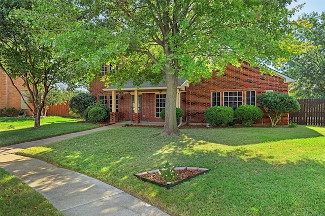 view of front facade with brick siding, covered porch, a front yard, and fence