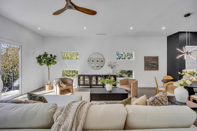 living room featuring ceiling fan with notable chandelier and hardwood / wood-style flooring