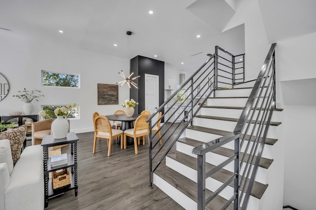 stairs featuring a high ceiling, a notable chandelier, and hardwood / wood-style flooring