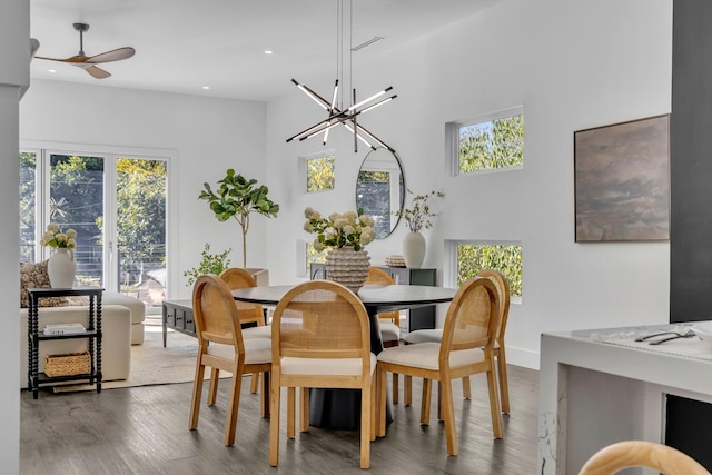 dining area with hardwood / wood-style floors and ceiling fan with notable chandelier