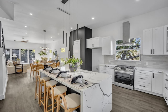 kitchen with island exhaust hood, gas range, white cabinets, and pendant lighting