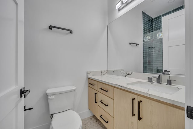 bathroom with a tile shower, vanity, and toilet