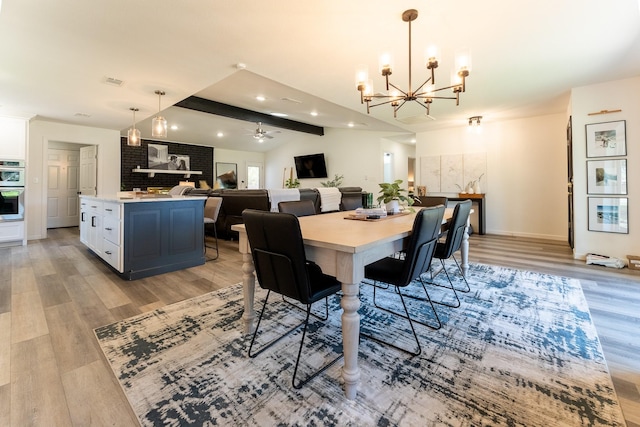 dining space with vaulted ceiling with beams, ceiling fan with notable chandelier, and light hardwood / wood-style floors