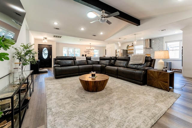 living room with ceiling fan with notable chandelier, lofted ceiling with beams, and hardwood / wood-style flooring