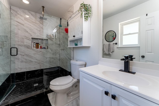 bathroom featuring a shower with door, vanity, and toilet