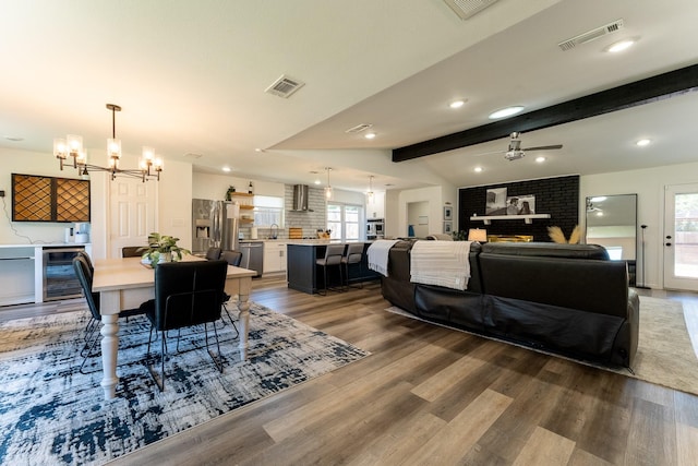 living room with hardwood / wood-style flooring, ceiling fan with notable chandelier, vaulted ceiling with beams, and beverage cooler