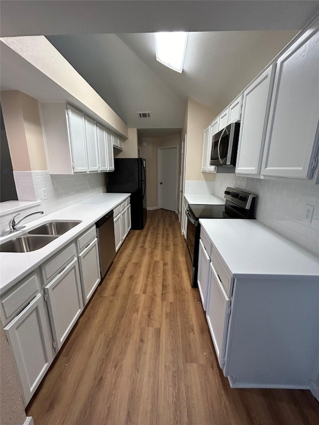 kitchen with backsplash, white cabinetry, sink, and black appliances