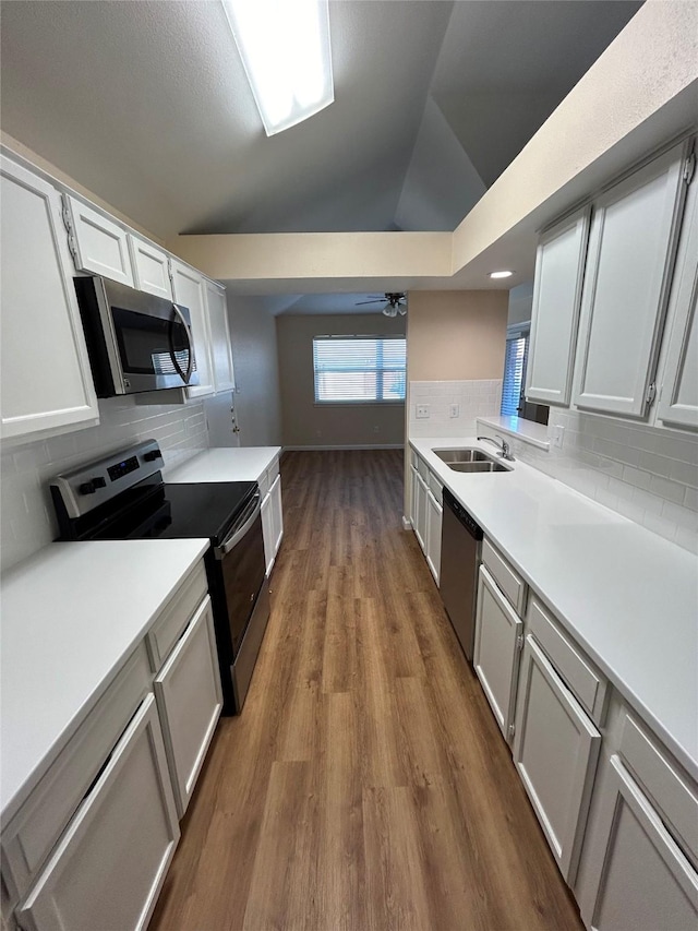 kitchen with sink, decorative backsplash, ceiling fan, white cabinetry, and stainless steel appliances