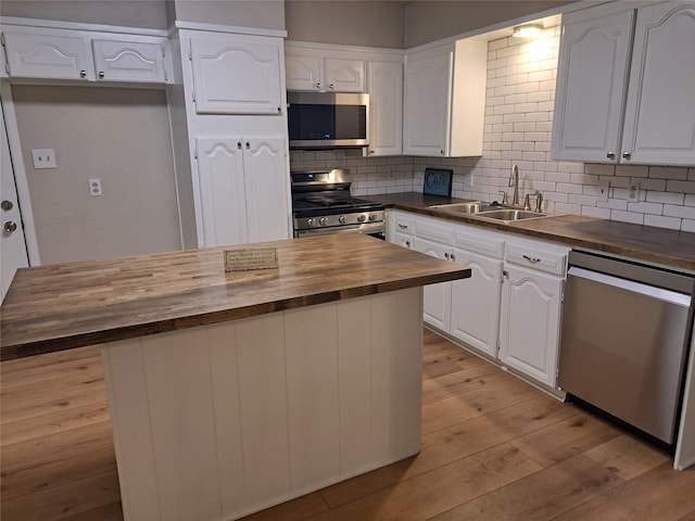 kitchen featuring wooden counters, decorative backsplash, stainless steel appliances, sink, and white cabinets