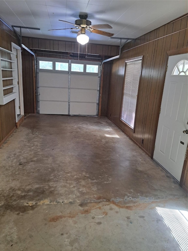 garage featuring ceiling fan and wooden walls