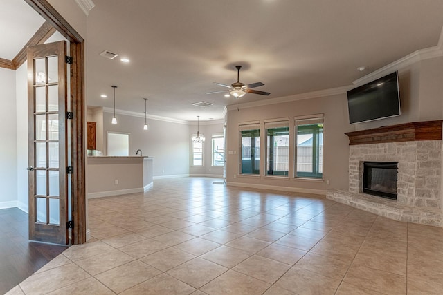 unfurnished living room with crown molding, a fireplace, light tile patterned floors, and ceiling fan with notable chandelier