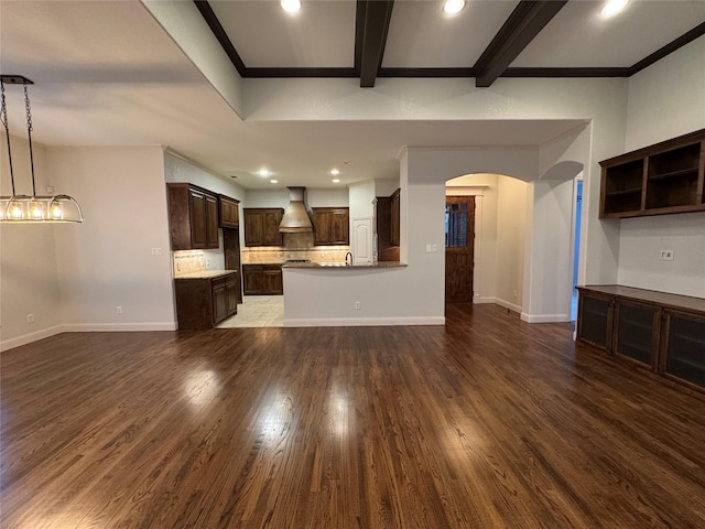 unfurnished living room with crown molding, beam ceiling, sink, and dark wood-type flooring