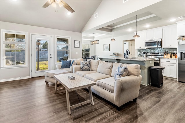 living room featuring a tray ceiling, ceiling fan, dark wood-type flooring, and sink