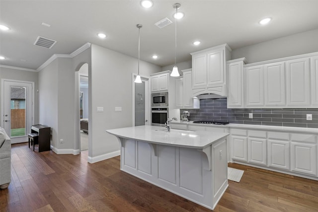 kitchen with appliances with stainless steel finishes, a center island with sink, white cabinetry, and pendant lighting